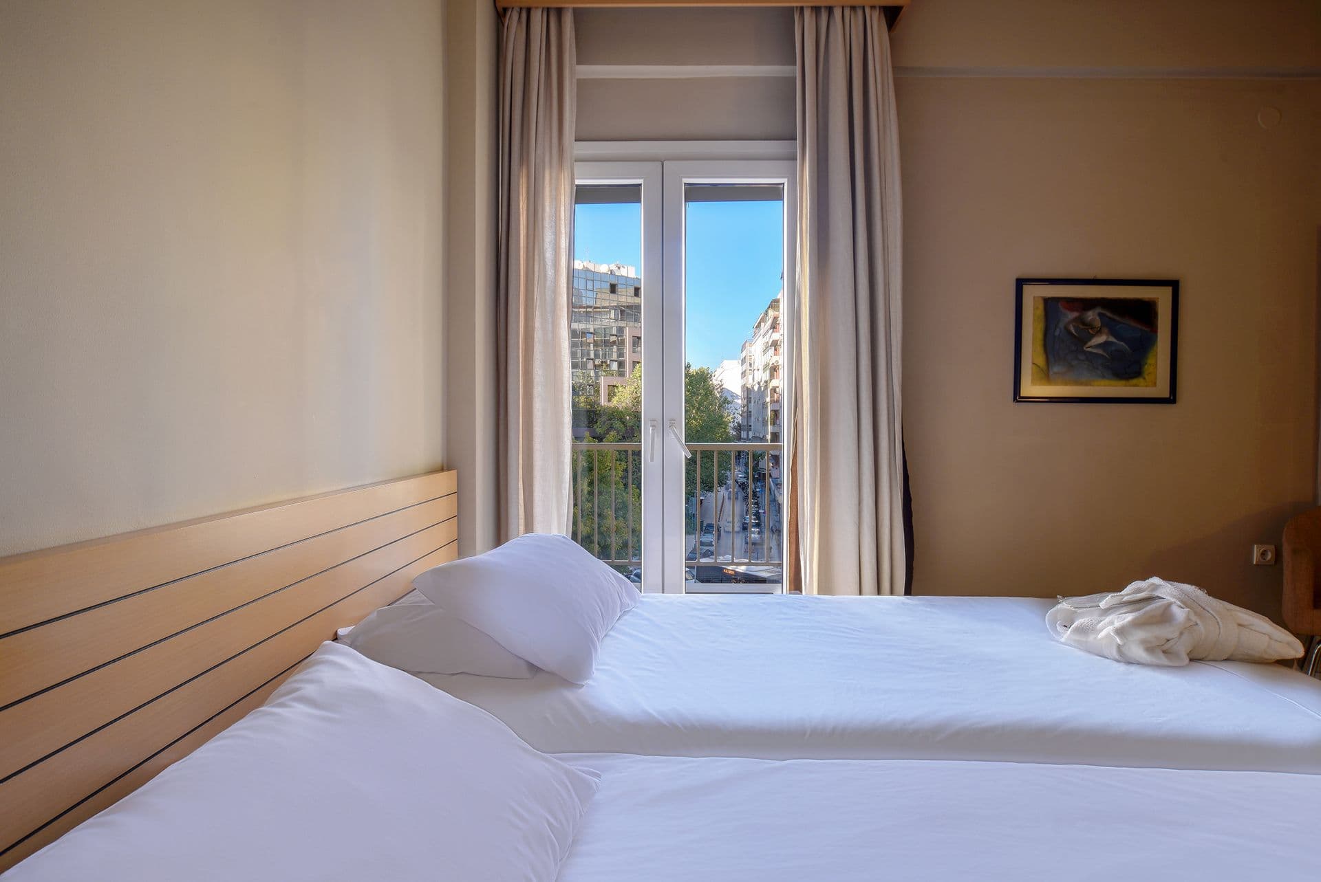 The bright light city view rooms at Astoria Hotel Thessaloniki offer a serene yet vibrant retreat, combining modern elegance with natural charm. Large windows bathe the space in abundant natural light, showcasing stunning views of Thessaloniki's lively ci